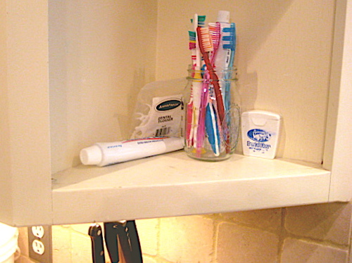 Children's toothbrushes next to the kitchen sink.
